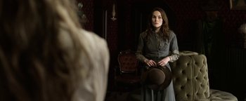 Movie still from “Godless” (2017), directed by Scott Frank – A woman holding a hat in front of a mirror; Medium shot, Over the shoulder angle