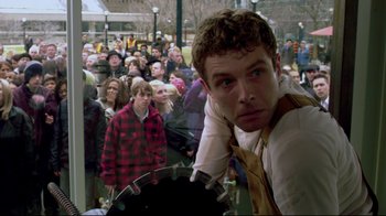 Movie still from “Saw 3D” (2010), directed by Kevin Greutert – A man standing in front of a group of people; Medium shot, Over the shoulder angle