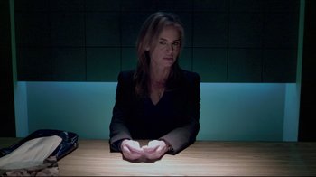 Movie still from “Saw 3D” (2010), directed by Kevin Greutert – A woman sitting at a table in front of a light; Medium shot, Over the shoulder angle