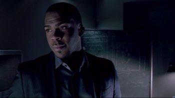 Movie still from “Saw 3D” (2010), directed by Kevin Greutert – A man standing in a dark room wearing a suit and tie; Close Up shot, Low angle