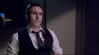 Movie still from “Saw 3D” (2010), directed by Kevin Greutert – A man wearing a suit and tie sitting in a room; Medium shot, Over the shoulder angle