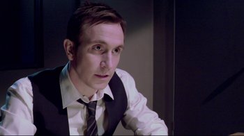 Movie still from “Saw 3D” (2010), directed by Kevin Greutert – A person wearing a suit and tie; Close Up shot, Over the shoulder angle