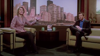 Movie still from “Saw 3D” (2010), directed by Kevin Greutert – Two people sitting in chairs in front of a large screen tv; Wide shot, Over the shoulder angle