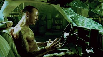 Movie still from “Saw 3D” (2010), directed by Kevin Greutert – A shirtless man sitting in the drivers seat of a car; Medium shot, High angle