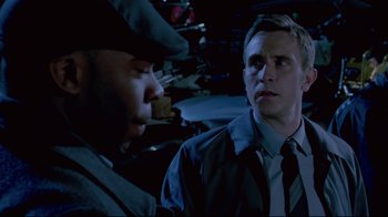 Movie still from “Saw 3D” (2010), directed by Kevin Greutert – A man in a hat and a jacket is looking at another man in a hat and a jacket; Close Up shot, Over the shoulder angle