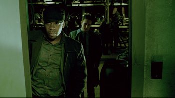 Movie still from “Saw 3D” (2010), directed by Kevin Greutert – Two men are standing in a room in a warehouse; Medium shot, Low angle