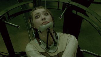 Movie still from “Saw 3D” (2010), directed by Kevin Greutert – A woman sitting in an operating room with an electric device attached to her head; Close Up shot, Overhead angle