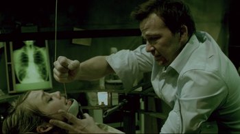 Movie still from “Saw 3D” (2010), directed by Kevin Greutert – A man is cutting a woman's hair with scissors; Medium shot, Low angle