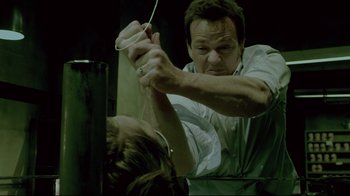 Movie still from “Saw 3D” (2010), directed by Kevin Greutert – A man holding a pair of headphones over a woman's head; Close Up shot, Over the shoulder angle