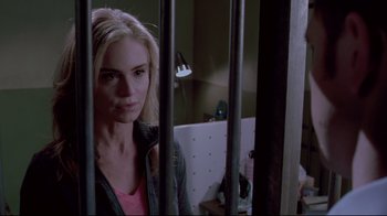 Movie still from “Saw 3D” (2010), directed by Kevin Greutert – A woman standing behind bars in a room; Close Up shot, Over the shoulder angle