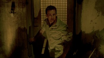 Movie still from “Saw 3D” (2010), directed by Kevin Greutert – A man in a white shirt is standing in a room; Medium shot, Low angle