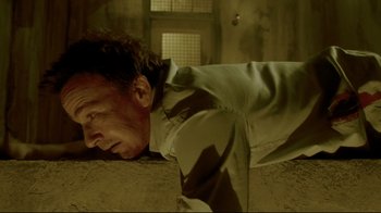 Movie still from “Saw 3D” (2010), directed by Kevin Greutert – A man is laying on the ground in a room; Close Up shot, Low angle