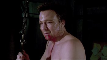 Movie still from “Saw 3D” (2010), directed by Kevin Greutert – A shirtless man with a chain around his neck; Close Up shot, Low angle