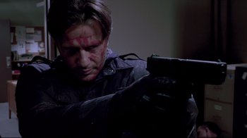 Movie still from “Saw 3D” (2010), directed by Kevin Greutert – A man in a black jacket is holding a gun; Close Up shot, Low angle