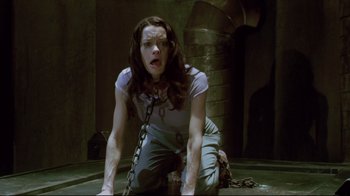 Movie still from “Saw 3D” (2010), directed by Kevin Greutert – A woman in chains crouching on the ground; Medium shot, High angle