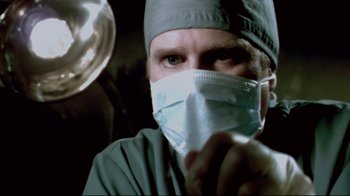 Movie still from “Saw 3D” (2010), directed by Kevin Greutert – A man wearing a surgical mask and a surgical cap; Close Up shot, Low angle