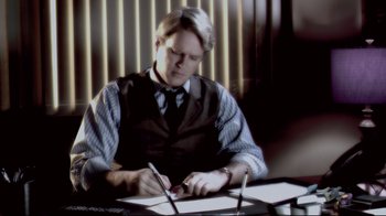 Movie still from “Saw 3D” (2010), directed by Kevin Greutert – A man sitting at a table writing on a piece of paper; Medium shot, Over the shoulder angle