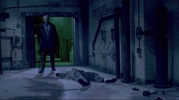 Movie still from “Saw 3D” (2010), directed by Kevin Greutert – A man standing next to a dead body in a room; Wide shot, Low angle