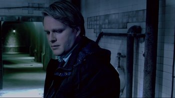Movie still from “Saw 3D” (2010), directed by Kevin Greutert – A man in a black jacket standing next to a wall; Close Up shot, Over the shoulder angle
