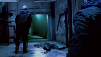 Movie still from “Saw 3D” (2010), directed by Kevin Greutert – A person is laying on the ground in a bathroom; Wide shot, Over the shoulder angle