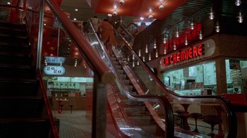 Movie still from “Scanners” (1981), directed by David Cronenberg – An escalator in a store with a person on it; Extreme Wide shot, High angle