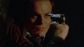 Movie still from “Scanners” (1981), directed by David Cronenberg – A person holding a gun; Close Up shot, Over the shoulder angle