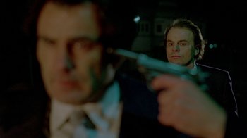 Movie still from “Scanners” (1981), directed by David Cronenberg – A man holding a gun in front of another man's face; Close Up shot, Low angle