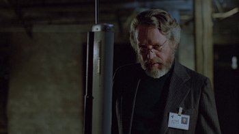 Movie still from “Scanners” (1981), directed by David Cronenberg – An older man with a beard and glasses in a suit; Medium shot, Over the shoulder angle