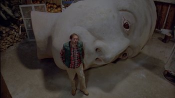 Movie still from “Scanners” (1981), directed by David Cronenberg – A man standing in front of an elephant statue; Wide shot, Low angle