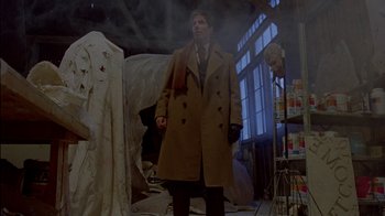 Movie still from “Scanners” (1981), directed by David Cronenberg – A man in a trench coat standing in a room; Wide shot, Low angle