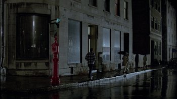 Movie still from “Scanners” (1981), directed by David Cronenberg – A group of people walking down the street in the rain; Extreme Wide shot, High angle