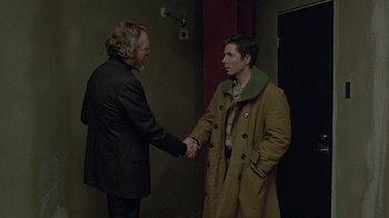 Movie still from “Scanners” (1981), directed by David Cronenberg – Two men shaking hands in a dark room; Medium shot, Over the shoulder angle