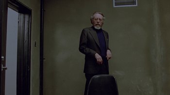 Movie still from “Scanners” (1981), directed by David Cronenberg – An older man standing in front of an empty chair; Medium shot, Over the shoulder angle