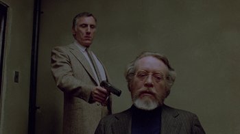 Movie still from “Scanners” (1981), directed by David Cronenberg – A man with a gun standing in front of another man; Medium shot, Over the shoulder angle