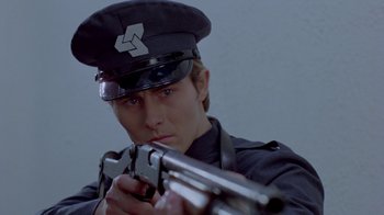 Movie still from “Scanners” (1981), directed by David Cronenberg – A man in a uniform holding a gun in his hands; Close Up shot, Low angle