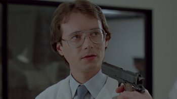 Movie still from “Scanners” (1981), directed by David Cronenberg – A man holding a gun up to his face; Close Up shot, Low angle