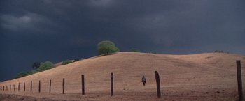 Movie still from “Scarecrow” (1973), directed by Jerry Schatzberg – A person standing in a field under a cloudy sky; Extreme Wide shot, High angle