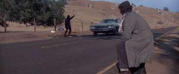 Movie still from “Scarecrow” (1973), directed by Jerry Schatzberg – A man riding a skateboard down the side of a road; Wide shot, Low angle