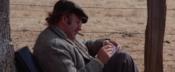 Movie still from “Scarecrow” (1973), directed by Jerry Schatzberg – A man sitting on the ground while smoking a cigarette; Close Up shot, Over the shoulder angle
