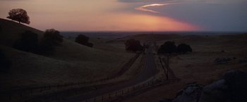 Movie still from “Scarecrow” (1973), directed by Jerry Schatzberg – A road going through the middle of a field at sunset; Extreme Wide shot, High angle