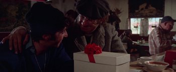 Movie still from “Scarecrow” (1973), directed by Jerry Schatzberg – A man and a woman looking at a gift box; Close Up shot, Over the shoulder angle
