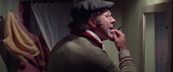 Movie still from “Scarecrow” (1973), directed by Jerry Schatzberg – A man in a hat and glasses eating a piece of food; Close Up shot, Over the shoulder angle