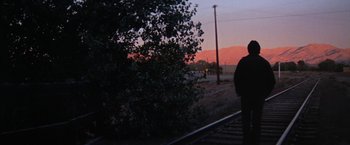 Movie still from “Scarecrow” (1973), directed by Jerry Schatzberg – A person standing on a train track near a tree; Wide shot, Low angle