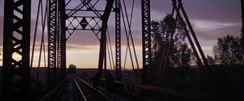 Movie still from “Scarecrow” (1973), directed by Jerry Schatzberg – A person riding a bike across a bridge; Extreme Wide shot, Low angle
