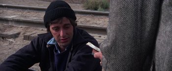 Movie still from “Scarecrow” (1973), directed by Jerry Schatzberg – A man sitting on the side of a train tracks; Close Up shot, Over the shoulder angle