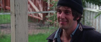 Movie still from “Scarecrow” (1973), directed by Jerry Schatzberg – A person wearing a hat and smiling; Close Up shot, Over the shoulder angle