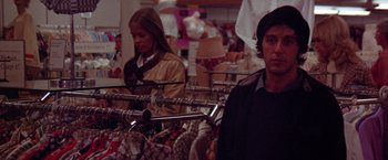 Movie still from “Scarecrow” (1973), directed by Jerry Schatzberg – A man and a woman in a store looking at a rack of clothes; Medium shot, Over the shoulder angle