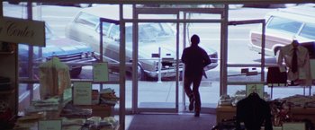 Movie still from “Scarecrow” (1973), directed by Jerry Schatzberg – A man walking through a glass door in a store; Wide shot, Low angle