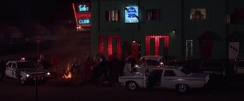 Movie still from “Scarecrow” (1973), directed by Jerry Schatzberg – A police car parked in front of a building with people walking around; Extreme Wide shot, High angle