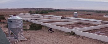 Movie still from “Scarecrow” (1973), directed by Jerry Schatzberg – A person kneeling on the ground in front of a building; Extreme Wide shot, High angle
